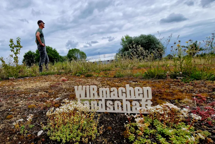 Schriftzug und Mann auf artenreicher Fläche