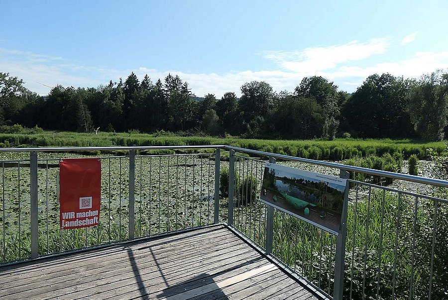 Rotes Störbanner an Terassenbrüstung mit Blick auf Weiher
