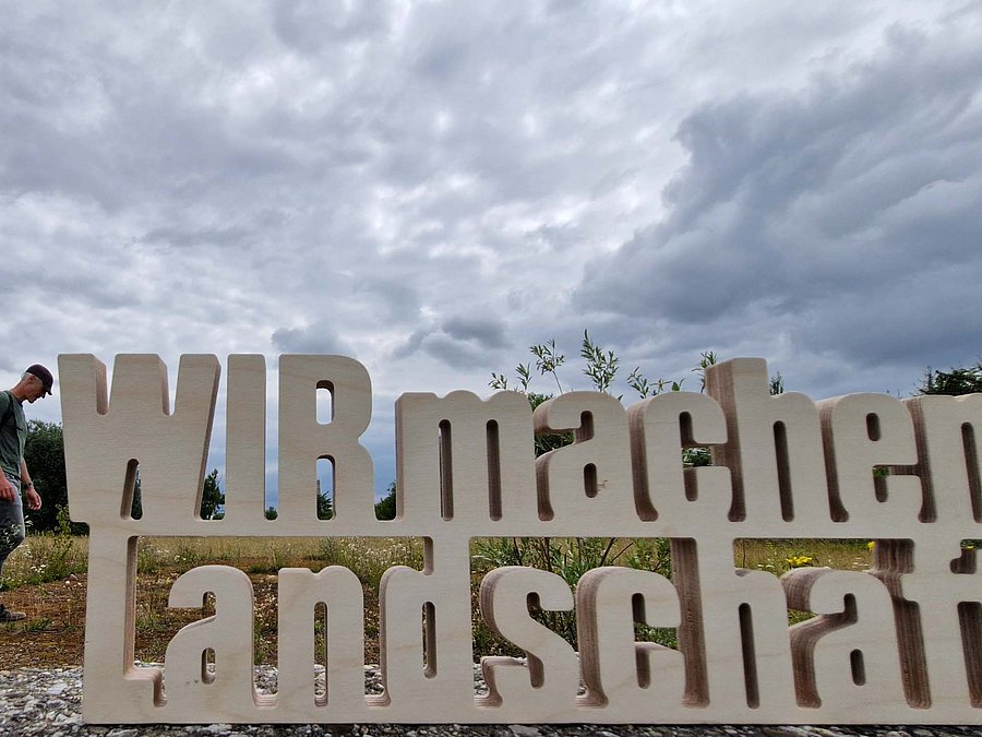 Schriftzug vor bewölktem Himmel