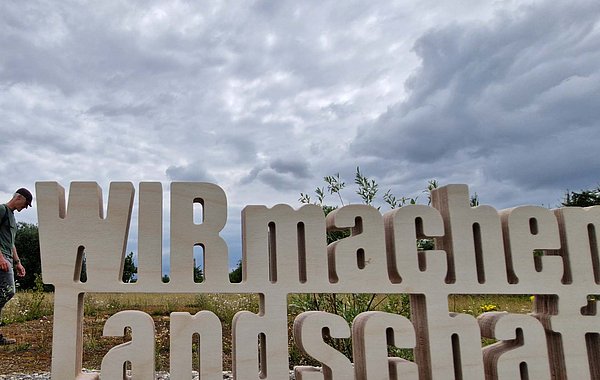 WIR machen Landschaft ©LPV Stadt Augsburg Schriftzug vor bewölktem Himmel
