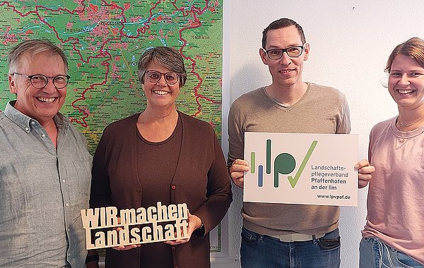 Vier Personen vor einer Landkarte mit Holzschild „WIR machen Landschaft“ und LPV-Logo