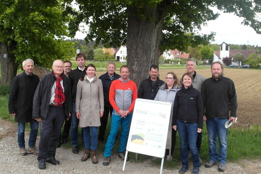 Menschengruppe steht vor einem Baum.