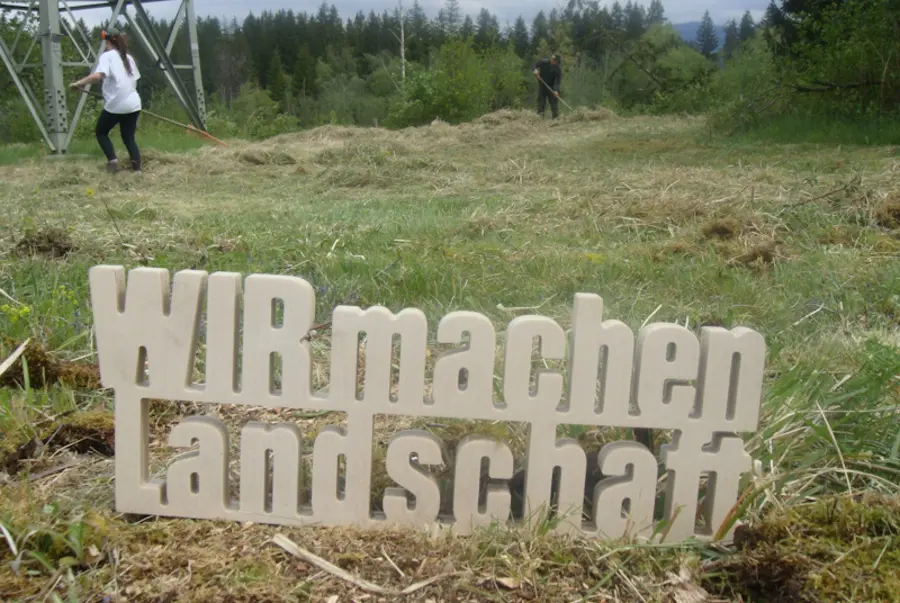 Schriftzug vor gemähter Wiese