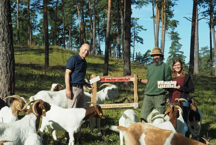 Personen mit Schriftzug in Ziegenherde