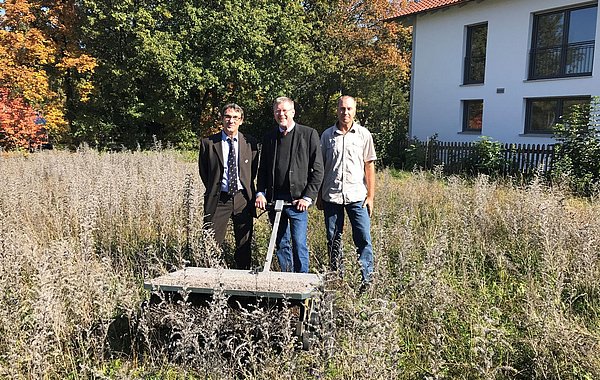 Projektstart in Altötting ©Sarah Irrgang, DVL Drei Personen stehen auf einer Wiese und ernten mit einer Maschine Saatgut.