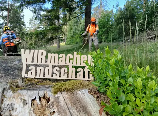 Schriftzug vor mähenden Personen