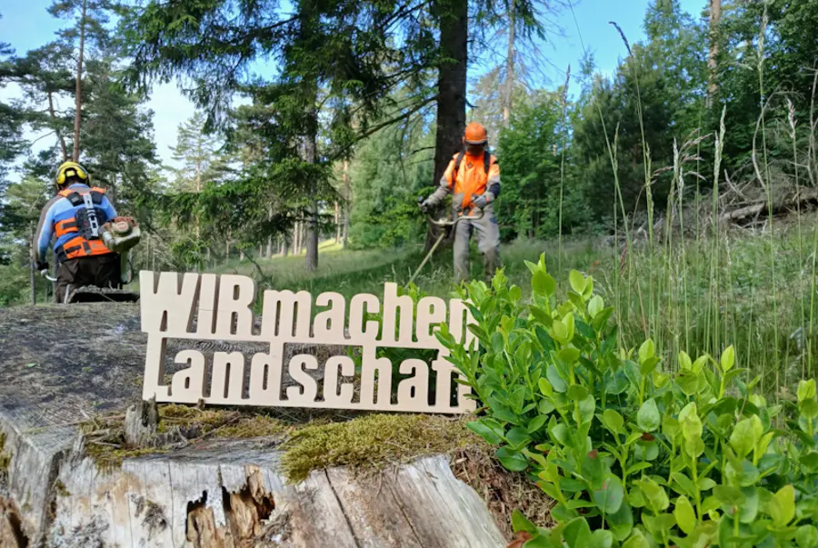 Schriftzug vor mähenden Personen