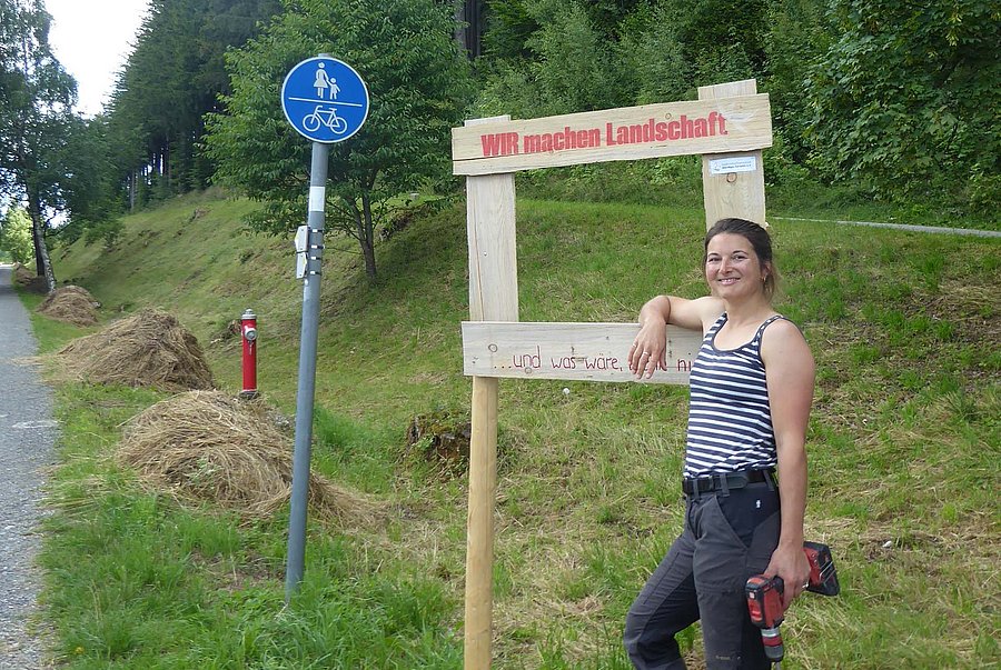Frau mit Akkuschrauber vor Holzrahmen