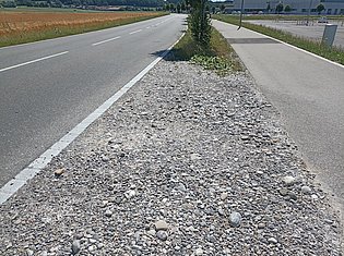 Mittelstreifen zwischen Strassen mit Schotter