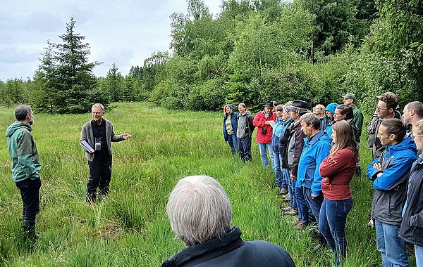 Exkursionsgruppe auf einer Streuobstwiese am Waldrand während eines fachlichen Austauschs
