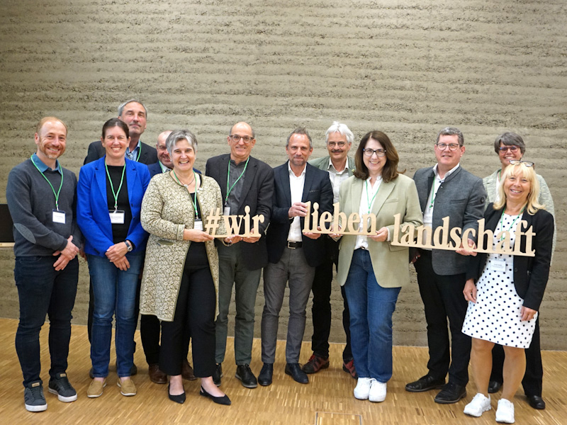 Teilnehmede des Bayerischen Landschaftspflegetags halten den Schriftzug #wirliebenlandschaft hoch.