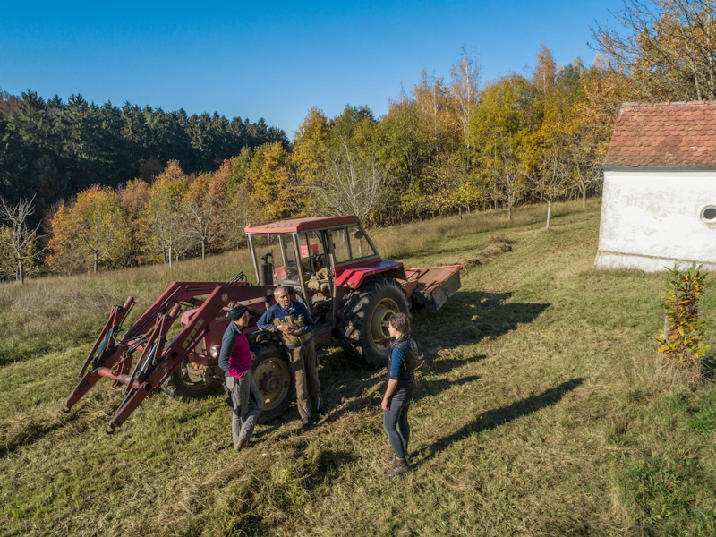 Traktor und ein Mann mit zwei Frauen, die sich unterhalten.
